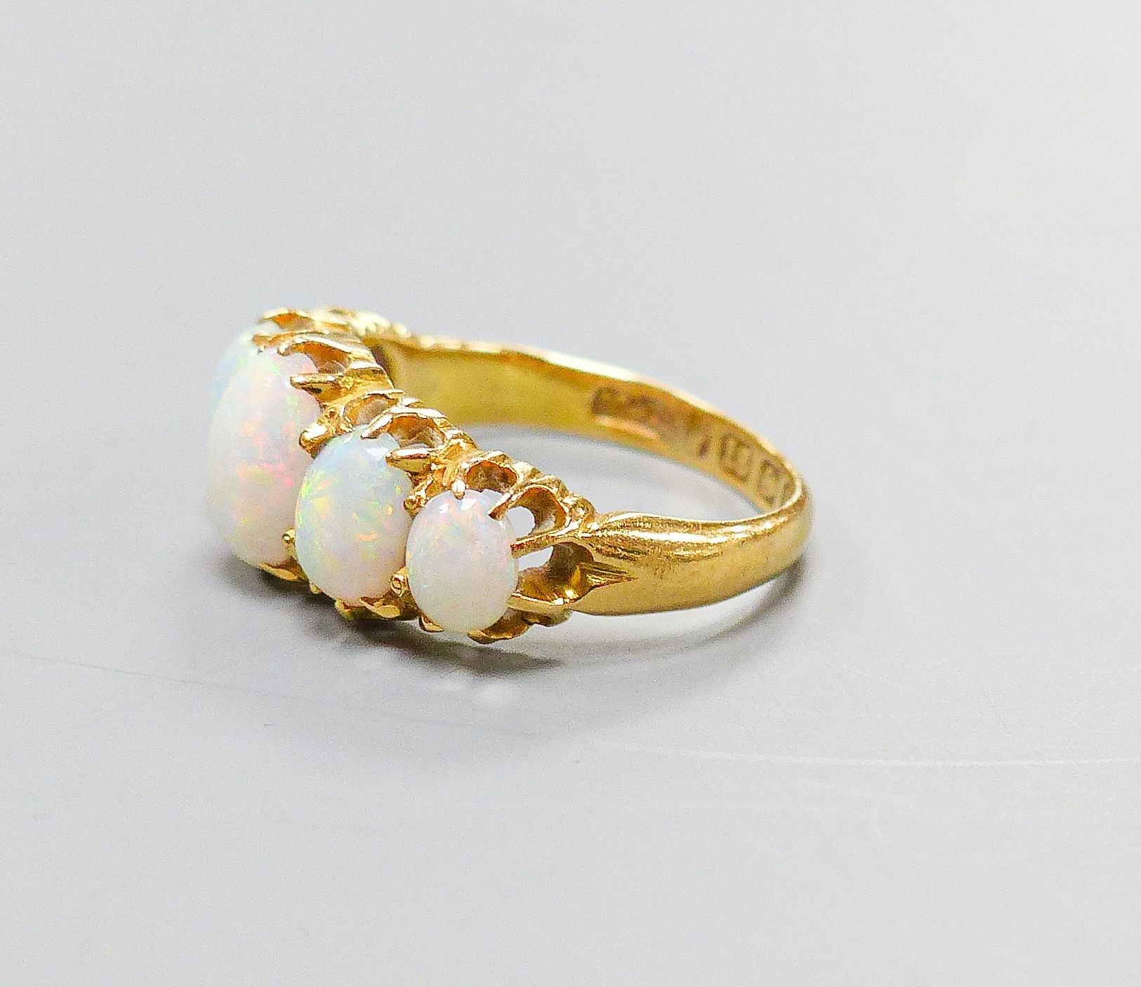 An Edwardian 18ct gold and graduated five stone white opal set half hoop ring, size K, gross 3.8 grams.